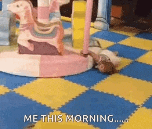 A Person Is Laying On The Floor In Front Of A Merry Go Round And Says Me This Morning . GIF