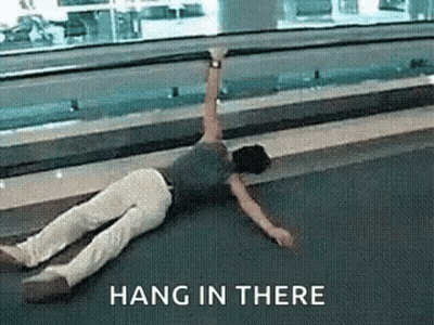A Person Is Laying On The Floor With A Sign That Says Hang In There Above Them . GIF