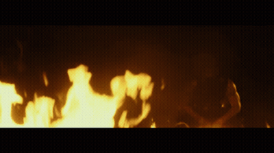 A Person Is Laying On The Ground In Front Of A Large Fire GIF