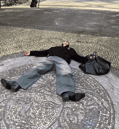A Person Is Laying On The Ground With A Black Bag GIF