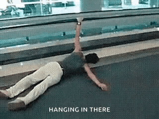 A Person Is Laying On The Ground With The Words Hanging In There Above Them . GIF