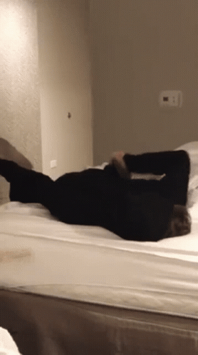 A Person Is Laying On Their Back On A Bed In A Bedroom GIF