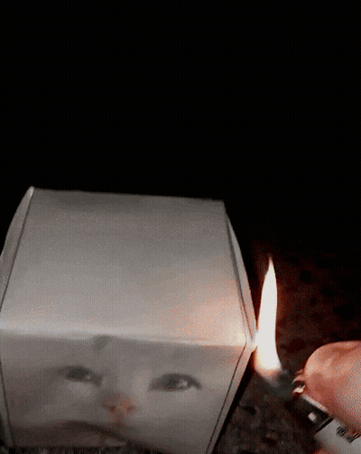 A Person Is Lighting A Lighter Next To A Box With A Picture Of A Face On It GIF