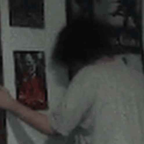 A Person Is Looking At A Picture On A Wall In A Room . GIF