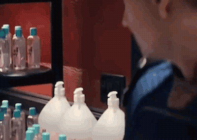 A Person Is Looking At Bottles Of Hand Sanitizer In A Store . GIF