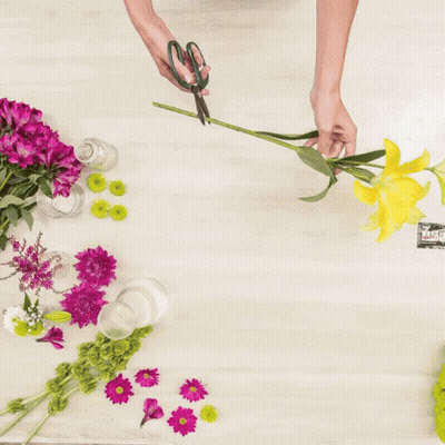 A Person Is Making A Bouquet Of Flowers With Purple And White Flowers GIF