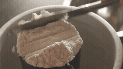 A Person Is Measuring Flour In A Measuring Cup With A Knife GIF