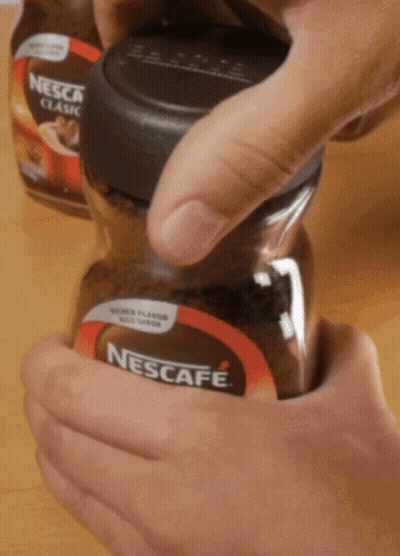 A Person Is Opening A Jar Of Nescafe Classic GIF