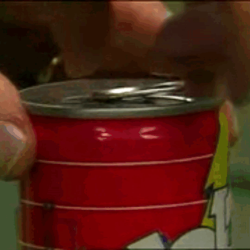 A Person Is Opening A Red Can Of Soda With A Lightning Bolt On It GIF