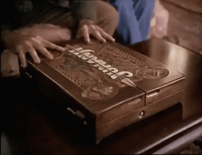 A Person Is Opening A Wooden Box That Says Jurassic Park On It GIF