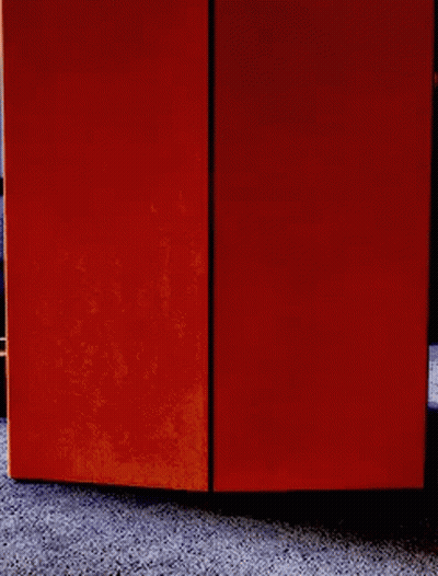 A Person Is Peeking Out From Behind An Orange Box On The Floor . GIF