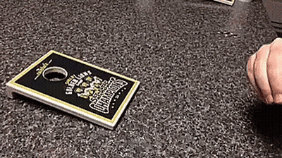 A Person Is Playing A Game Of Cornhole On A Counter Top GIF