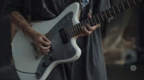 A Person Is Playing A White Guitar With A Sticker On The Bottom That Says ' Let 'S Talk Rock ' GIF