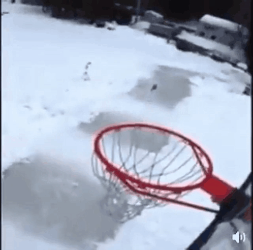 A Person Is Playing Basketball In The Snow With A Red Rim GIF