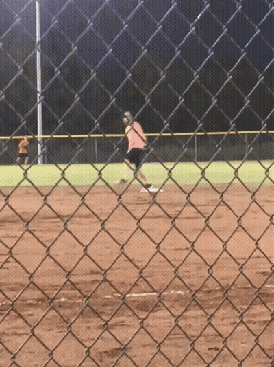 A Person Is Playing Softball On A Field Behind A Chain Link Fence GIF