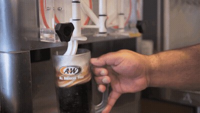 A Person Is Pouring A Beverage From A Machine That Says Aw GIF