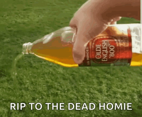 A Person Is Pouring A Bottle Of Olde English Apple Cider On A Lush Green Field . GIF