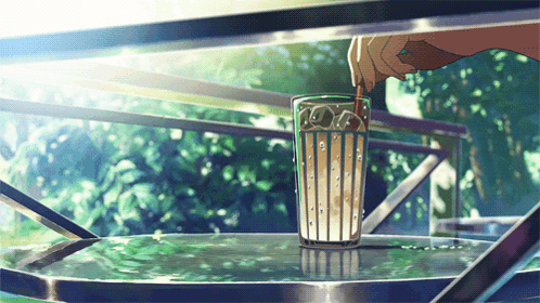 A Person Is Pouring A Drink Into A Glass On A Table GIF