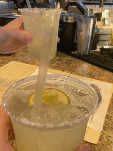 A Person Is Pouring A Drink Into A Plastic Cup With A Straw GIF