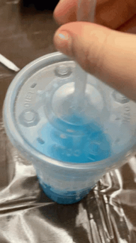 A Person Is Pouring Blue Liquid Into A Plastic Cup With A Straw GIF