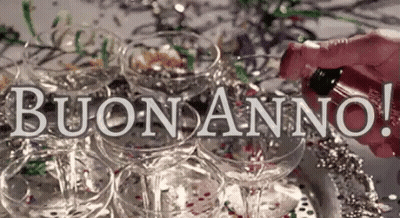 A Person Is Pouring Champagne Into A Pyramid Of Champagne Glasses With The Words Buon Anno In The Background . GIF