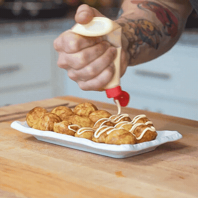 A Person Is Pouring Mayonnaise On A Plate Of Fried Food GIF