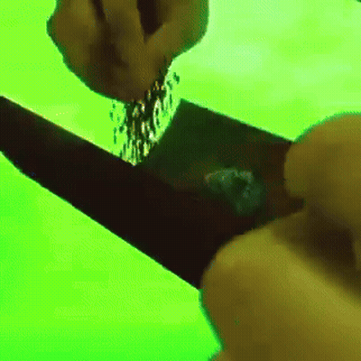 A Person Is Pouring Something Into A Black Object On A Green Screen GIF