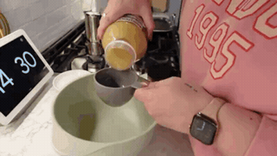 A Person Is Pouring Something Into A Bowl . GIF