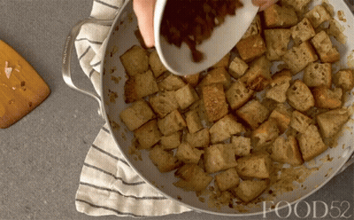 A Person Is Pouring Something Into A Pan Of Food52 Croutons GIF