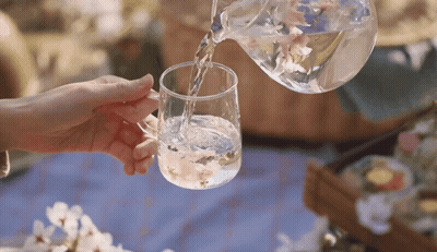 A Person Is Pouring Water Into A Glass Cup GIF