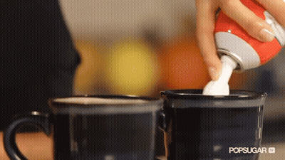 A Person Is Pouring Whipped Cream Into Two Coffee Cups GIF
