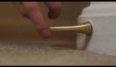 A Person Is Pressing A Door Stop On A Carpet . GIF