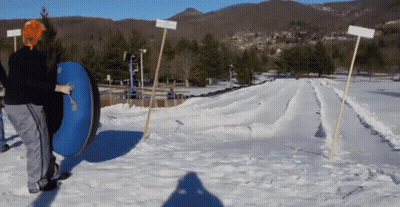 A Person Is Pushing A Blue Tube Down A Snow Covered Hill GIF