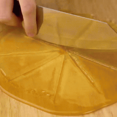 A Person Is Putting A Doughnut On Top Of A Chocolate Cake On A Wooden Cutting Board . GIF