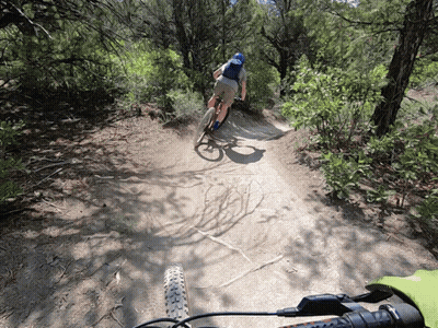 A Person Is Riding A Bike Down A Dirt Path GIF