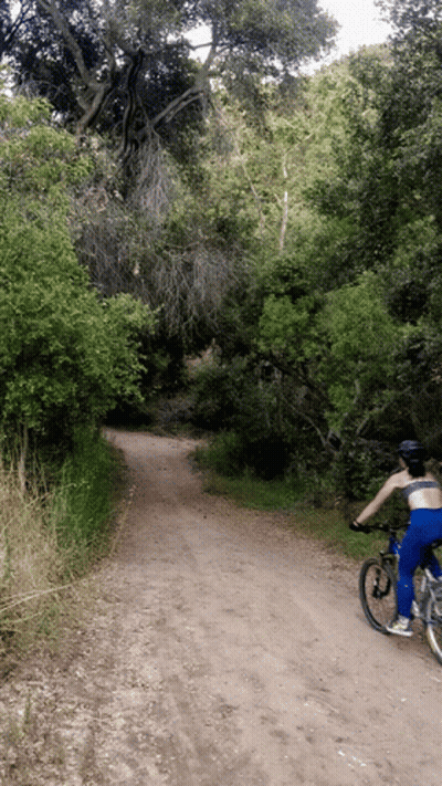 A Person Is Riding A Bike Down A Dirt Road GIF