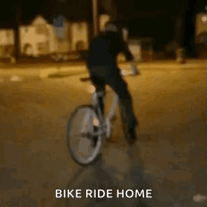 A Person Is Riding A Bike On A Street At Night . GIF