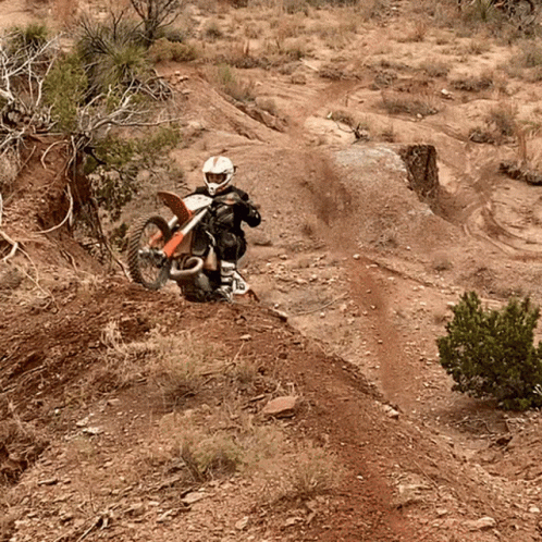 A Person Is Riding A Dirt Bike Down A Dirt Road GIF