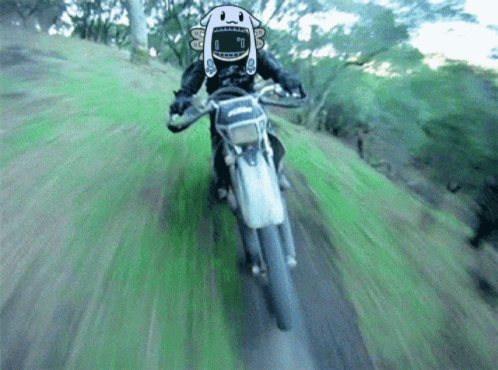 A Person Is Riding A Dirt Bike With A Cartoon Character On Their Face GIF