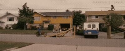 A Person Is Riding A Motorcycle Down A Ramp In Front Of A House . GIF