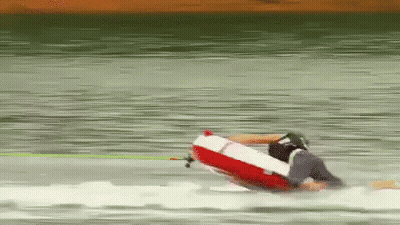 A Person Is Riding A Red And White Raft On A Lake GIF