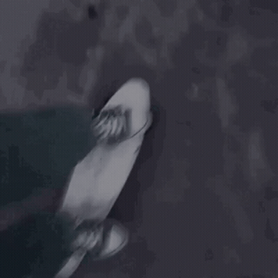 A Person Is Riding A Skateboard Down A Dark Street . GIF