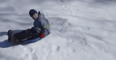 A Person Is Riding A Sled Down A Snow Covered Hill GIF