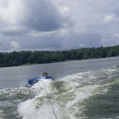 A Person Is Riding A Tube On A Lake GIF