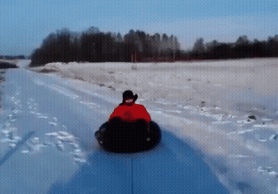 A Person Is Riding Down A Snow Covered Road On A Snow Tube GIF