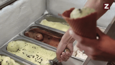 A Person Is Scooping Ice Cream Out Of A Cone With A Spoon .. GIF