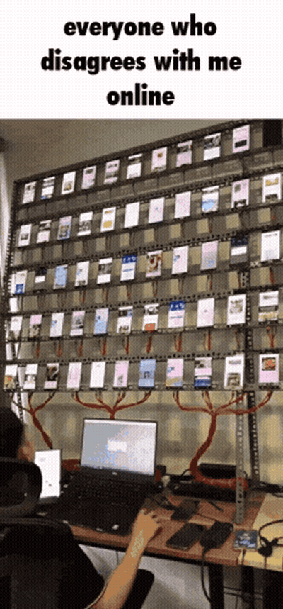 A Person Is Sitting At A Desk With A Laptop In Front Of A Wall Full Of Cell Phones GIF
