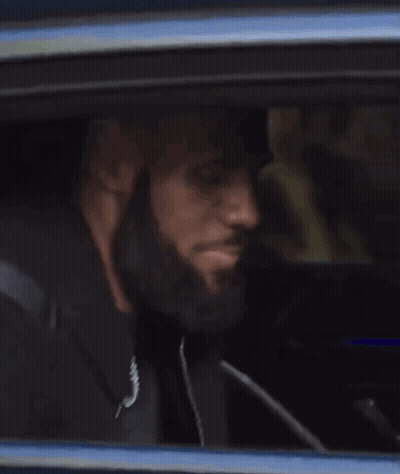 A Person Is Sitting In A Car Looking Out Of The Window . GIF