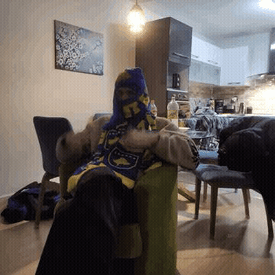 A Person Is Sitting In A Chair Wearing A Scarf Around Their Head . GIF