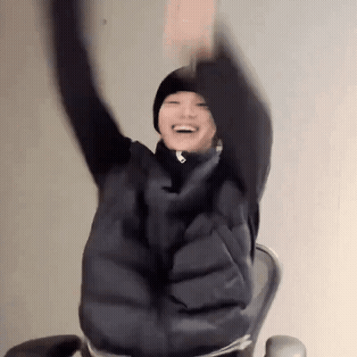 A Person Is Sitting In A Chair With Their Arms Up In The Air . GIF